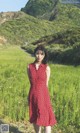 A woman in a red dress standing in a field.