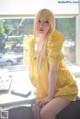 A woman in a yellow dress sitting on a window sill.