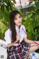 A woman in a school uniform sitting on a bench.