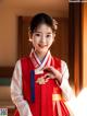 A young girl in a red and white hanbok poses for a picture.