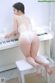 A woman in a yellow and white striped swimsuit sitting on a white piano.