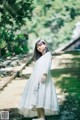 A woman in a white dress standing on some steps.