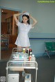 A woman in a white uniform standing next to a hospital bed.