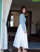 A woman standing in front of a door wearing a white skirt.