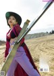 A woman in a red jacket and purple pants holding a sword.