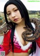 A woman holding a large snake in her arms.