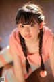 A young woman with long black hair sitting on the floor.