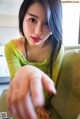 A woman in a green shirt is sitting on a couch.