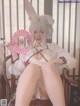 A woman in a bunny costume sitting on a chair holding a fan.