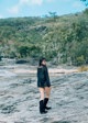 A woman standing on top of a large rock.