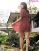 A woman in a red dress standing in front of a house.