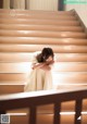 A woman in a white dress sitting on a set of stairs.