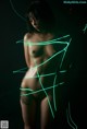 A naked woman standing in front of a black background.